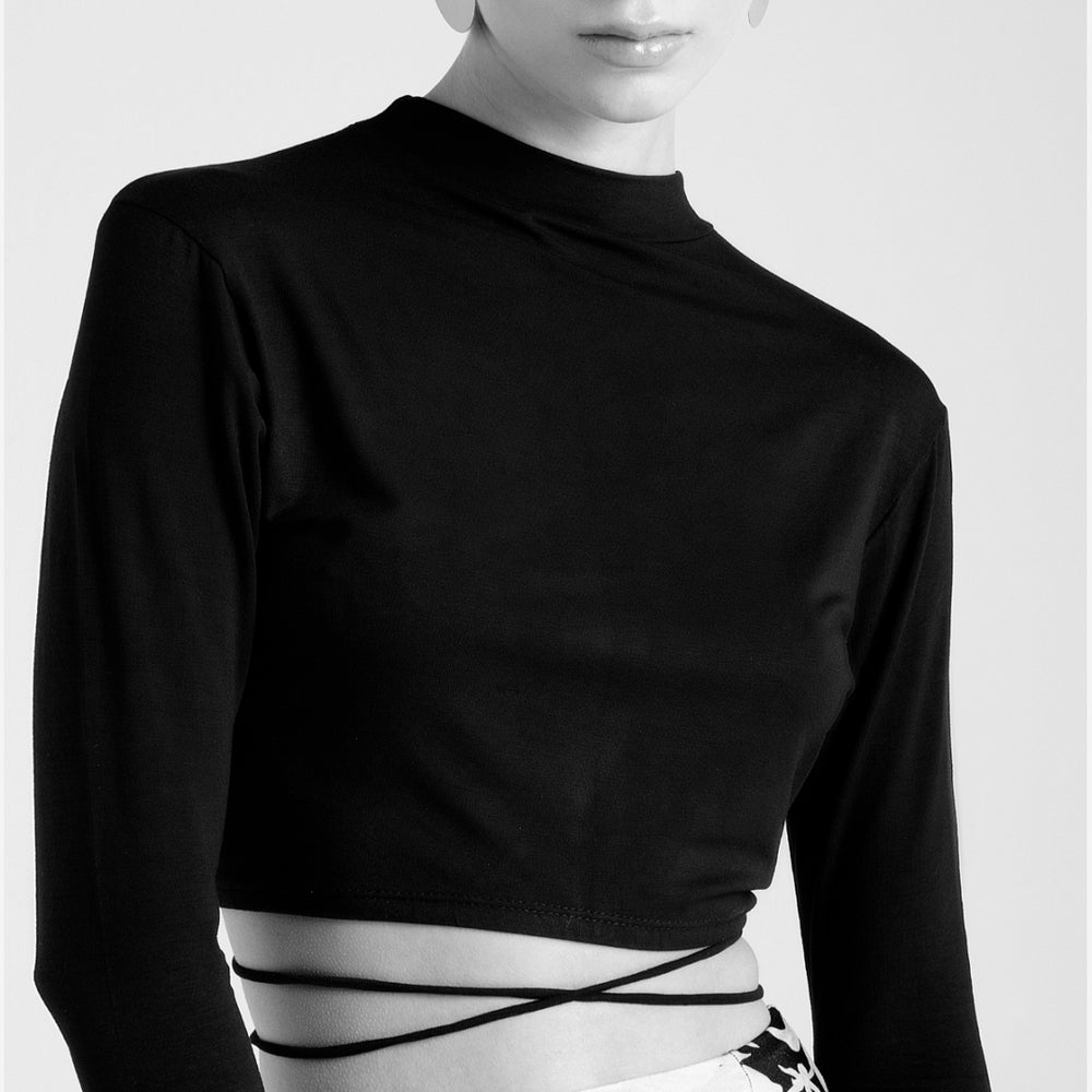 B&w photo. Model wears a black long sleeved  cropped cotton top with stripes around the waist