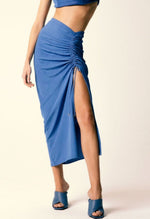 Model wears a blue bandeau top and 3/4 blue skirt with adjustable tie stripes on the left leg